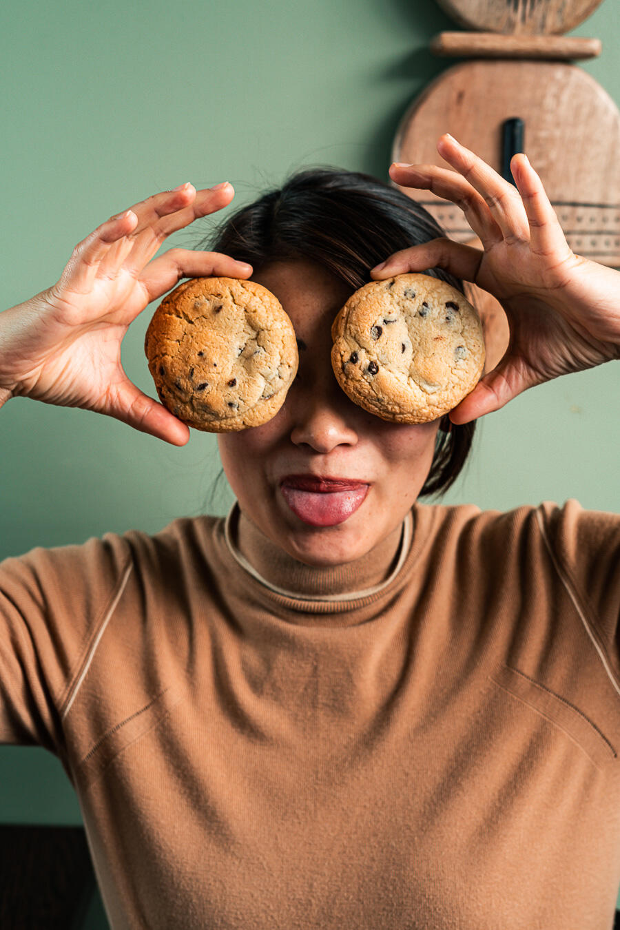 femme qui tient deux cookies devant ses yeux