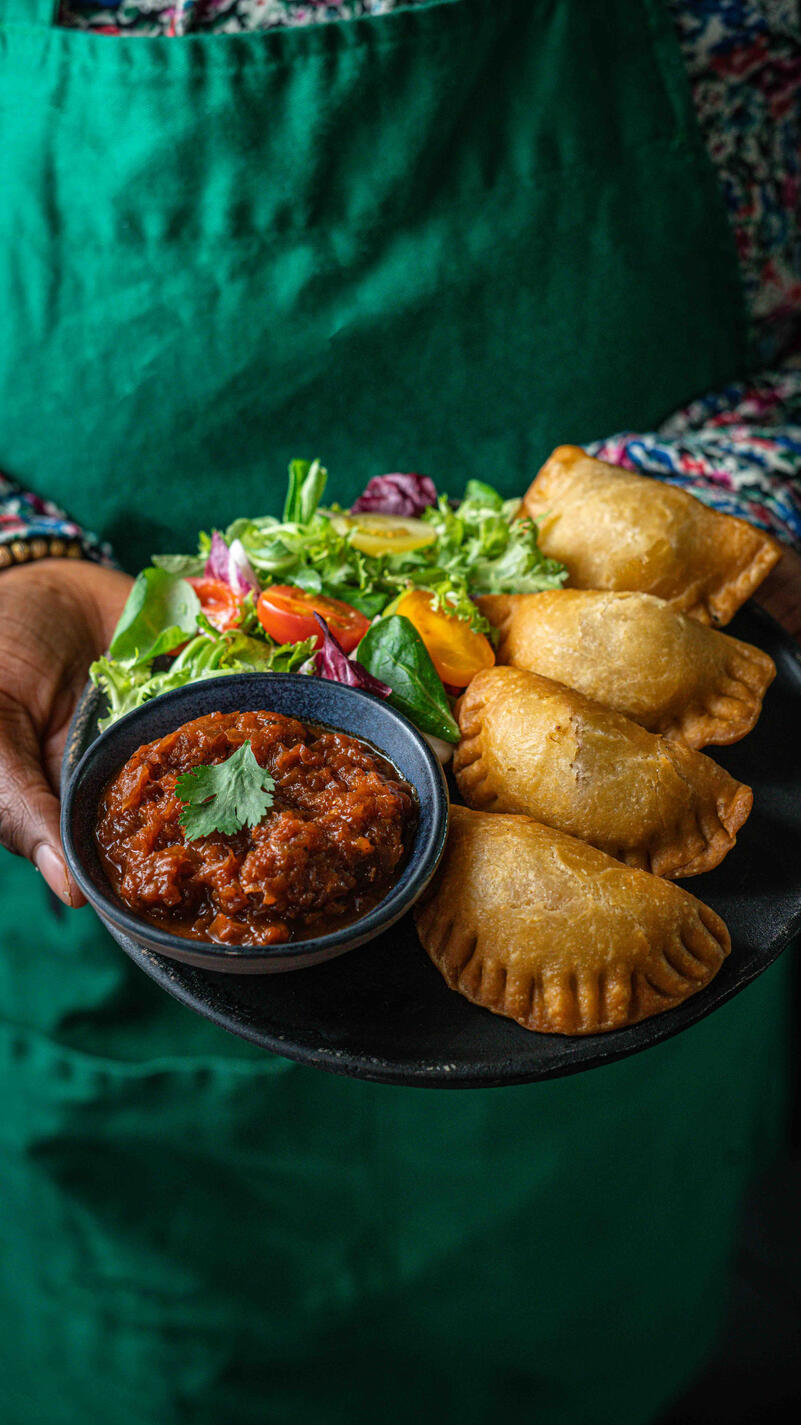 serveuse qui tient un plat de empanadas avec salade